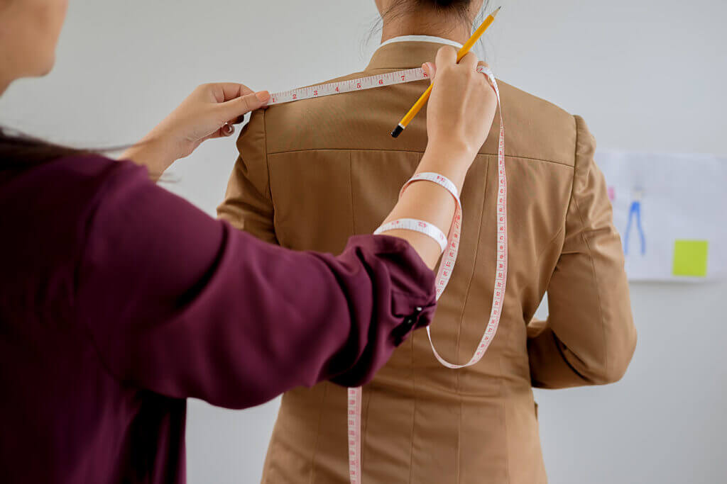 A staff member measures a player’s shoulders for the jersey